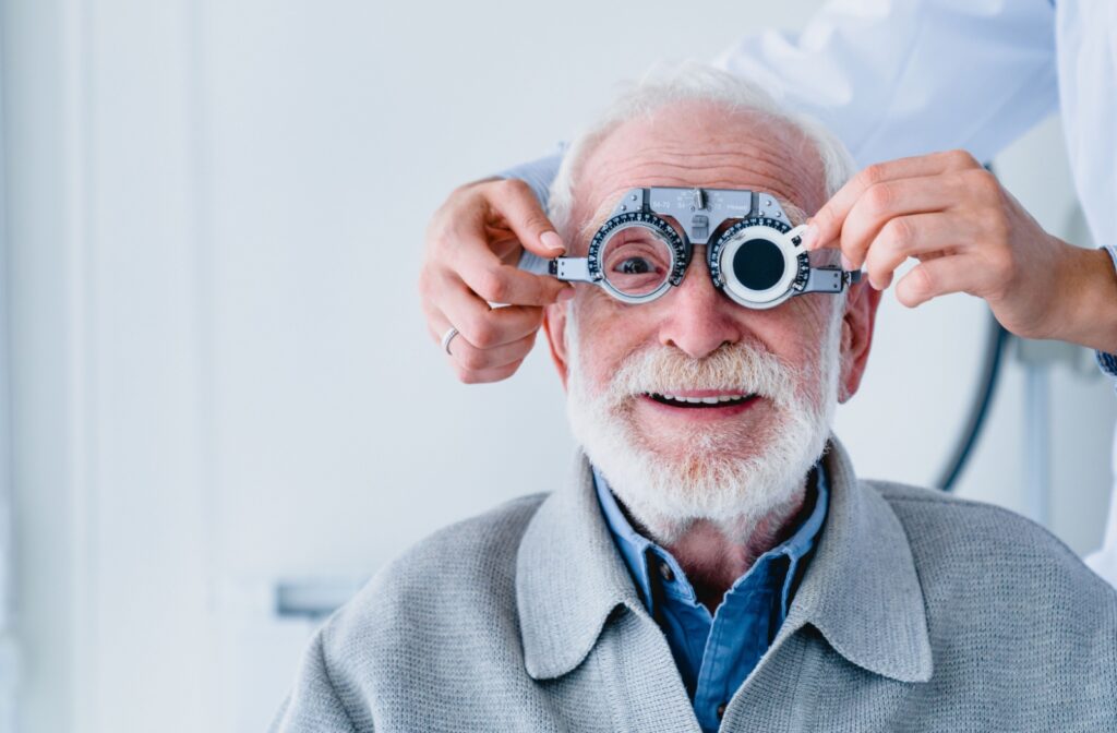 An optometrist adjusting their senior patient's optical lenses during a routine eye exam.