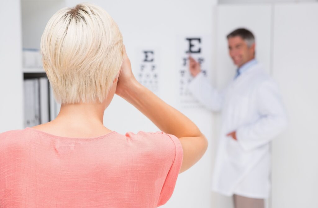 A patient covers one eye and reads off an eye chart during their routine eye exam to measure their visual acuity.